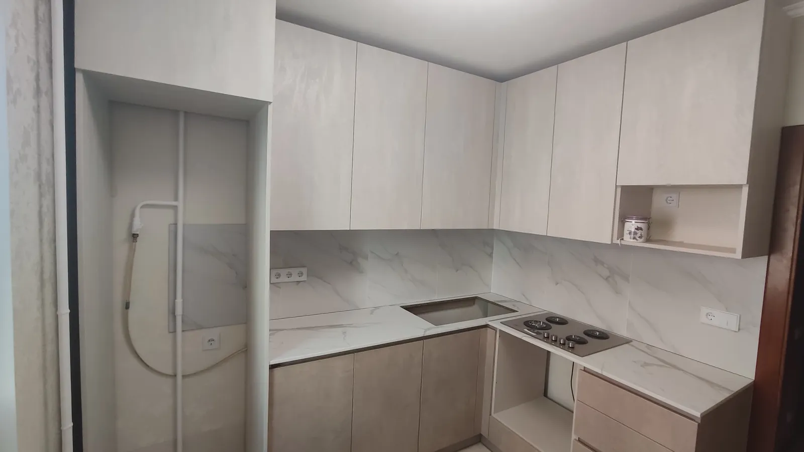 Made-to-measure corner kitchen — beige fronts, marble-look splashback and worktop